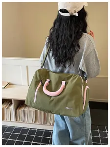 Detailansicht einer großen Reisetasche in Olivgrün mit rosa Griffen und Schultergurt.