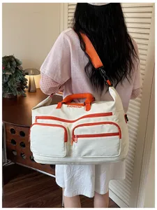 Detailed view of large capacity canvas duffel travel bag with orange zipper and pockets.