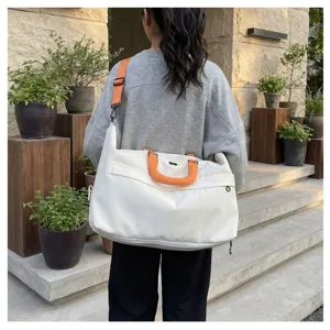 Large capacity travel duffel bag with orange handle and shoulder strap for outdoor use.