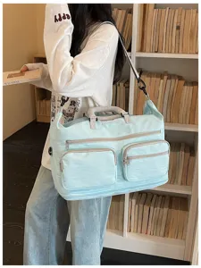 Detailed view of large capacity travel duffel bag in light blue with multiple zipper pockets.