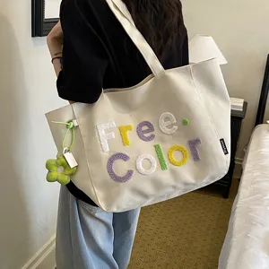 Casual canvas tote bag for women, stylish embroidered letter shoulder bag with cute flower pendant.