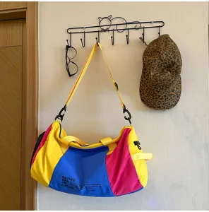 Detailed view of colorful travel duffel bag hanging on wall hook, showing stylish color block.