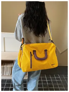 Gelbe Reise-Duffle-Bag Detailansicht, violetter Griffakzent und Vordertasche mit Reißverschluss.