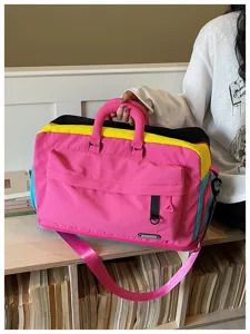 Dettaglio borsa da palestra color-block con vivace design in tessuto rosa, giallo e nero.