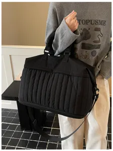 Grand sac de voyage noir matelasse avec un design elance et une sangle confortable.