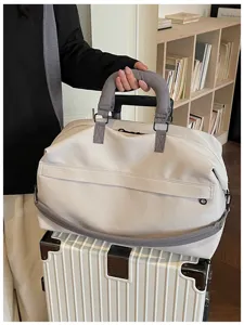 Close-up detail view of the casual beige travel duffel bag with grey handles on a luggage.
