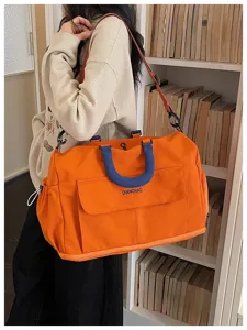Large capacity orange travel duffel bag with blue handles, front pocket and adjustable strap.