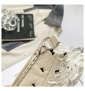 Detail view of cream bubble fabric bag featuring black bow patterns and silver chain
