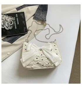 Detail view of the white seersucker underarm bag with a decorative organza bow