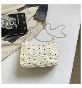 Detailed view of a white bubble fabric underarm bag featuring black bows and chain.