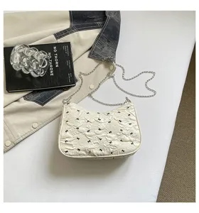 Close-up of white bubble gauze handbag with black bow patterns and silver chain strap