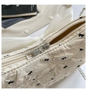 Detailed macro shot showing the bubble gauze fabric and silver zipper of a white bow tote bag