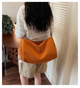 Crossbody gym travel bag detail showing large capacity, orange fabric and adjustable strap.