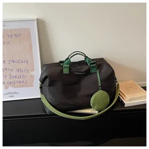 Vista dettagliata dell'elegante borsa da viaggio nera con cinghie e borsetta verdi a contrasto.