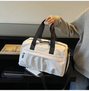 Detail view of large capacity white gym duffel bag with black handles and wet dry compartment.