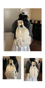 Beiger Kordelzug Rucksack Detail mit Fronttasche aus Netzgewebe und sicherem Schnallenverschluss.