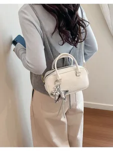 White leather bowling bag worn as a crossbody by a model in a casual indoor setting