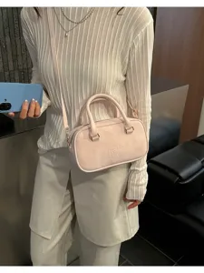 Close-up of pink bowling bag with embossed logo worn as crossbody