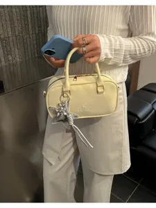 Close-up detail of cream women's bowling bag with embossed logo and silver star charm