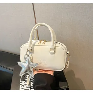 Detail view of a white women's bowling handbag with a silver star charm accessory