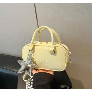 Close-up detail of a pale yellow bowling bag featuring a stylish silver star plush charm