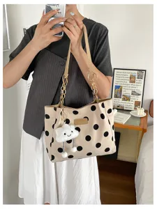 Detailed view of fashionable polka dot tote bag featuring chain straps and a plush cloud charm