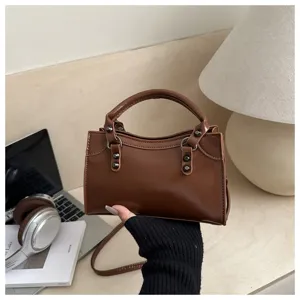 Detail view of a vintage brown rivet motorcycle bag held by hand in office setting