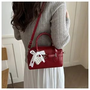 Detailansicht einer roten Leder Bowlingtasche mit weißer Spitzenschleife und Perle