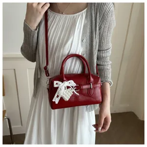Detailansicht einer stilvollen roten Bowling-Tasche mit weißer Spitzenschleife und Perlenherz.