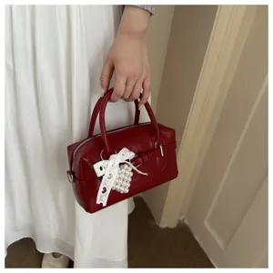 Rote Bowling-Handtasche mit Spitzen- und Perlenanhänger-Detail in der Hand