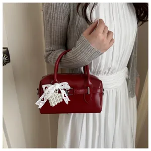 Detailansicht einer roten Bowlingtasche mit Spitzenschleife und Perlenherz-Anhänger, elegant.