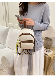 Mini sac à dos rétro blanc et marron tenu par un modèle dans un intérieur élégant