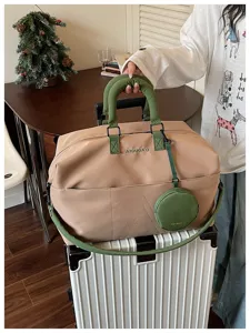 Dettaglio del borsone da viaggio cachi con manici verdi, tracolla e comoda borsetta rotonda.