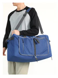Detailed view of large blue travel duffel bag showing model wearing it on shoulder outdoors.