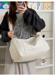Detail view of a large white travel gym bag with front zipper pocket and side storage compartment.