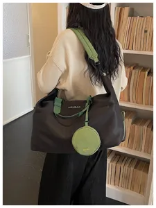 Vista dettagliata della borsa da viaggio nera casual con cinghie verdi e piccolo portamonete rotondo.