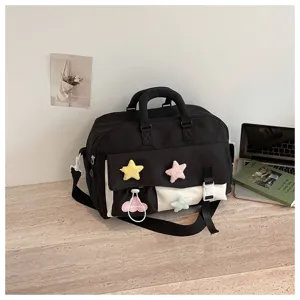 Details of black canvas travel duffel bag with cute plush star charms and dual handles.