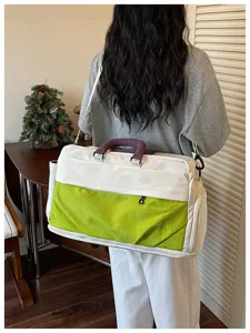 Detail view of large capacity travel duffel bag with green grid pocket in indoor scene.