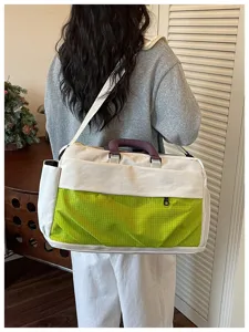 Detail view of a large-capacity canvas travel bag with green grid panel and purple handle.