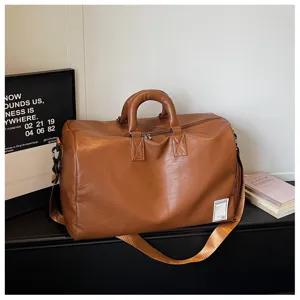 Braune Reise-Dufflebag aus Kunstleder im Detail, weiche Sporttasche mit verstellbarem Gurt