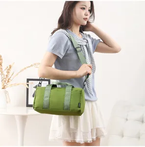 Small green cylindrical gym duffel bag detail, casual waterproof sports shoulder bag for women.