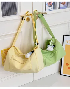 Large capacity canvas crossbody travel bag featuring cute plush pendant and zipper pocket.