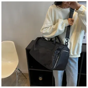 Minimalist black travel duffel bag detail, large capacity gym bag with shoe compartment.