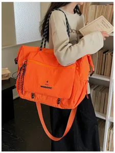 Close-up scene detail of the large orange travel shoulder bag displayed in a bookshelf room.