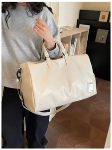 Detailansicht einer beigen Reisetasche aus weichem Leder mit bequemem Griff und Schultergurt.