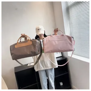 Close-up of large capacity travel duffel bags in pink and brown with shoulder strap.