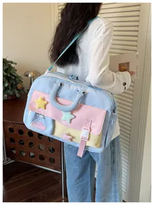Details of the pastel color-blocked travel duffel bag with cute plush star decorations.