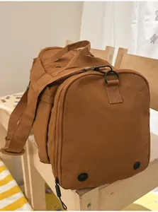 Duffle bag detail showing durable brown fabric, sturdy zippers, and shoulder strap attachment.