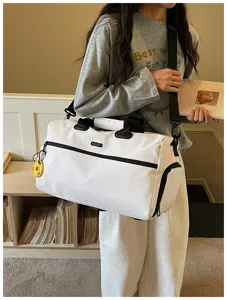 Détail en gros plan du sac de voyage blanc avec sangles noires durables et poche frontale.