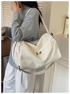 Detail shot of white canvas travel duffel bag showing side zipper pocket and dual straps.